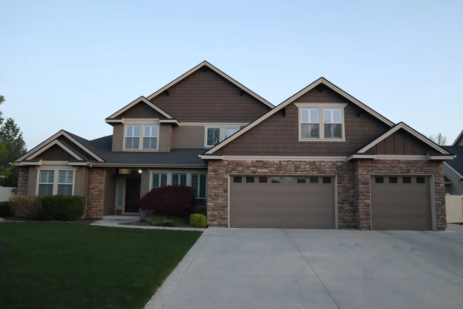 Brown two-storey home with stone accents in daylight, permanent LED track colour-matched and hidden along the eaves