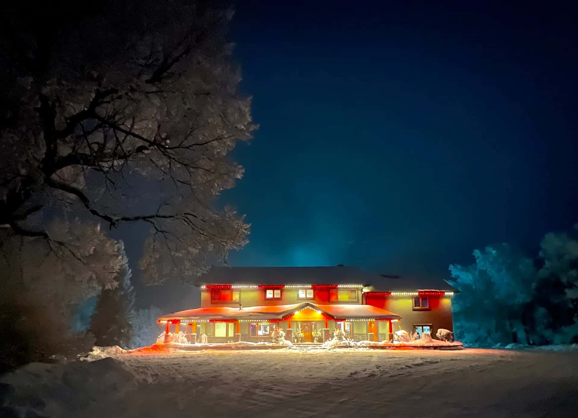 Two-storey home in fresh snow at night outlined in red and warm white permanent Christmas lights along every roofline - permanent LED lighting by Forever Lights, Southwestern Ontario