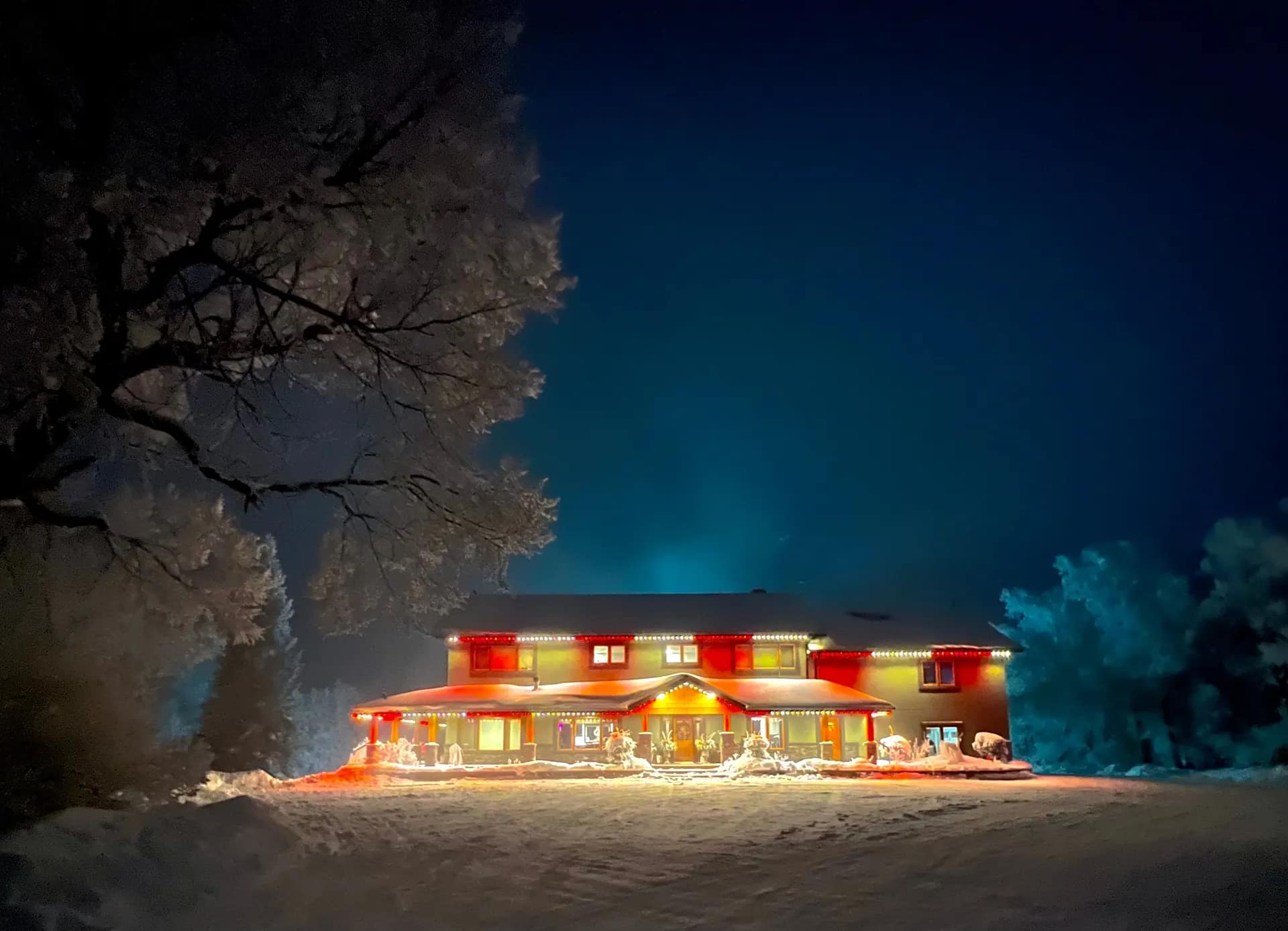Two-storey home in fresh snow at night outlined in red and warm white permanent Christmas lights along every roofline - permanent LED lighting by Forever Lights, Southwestern Ontario