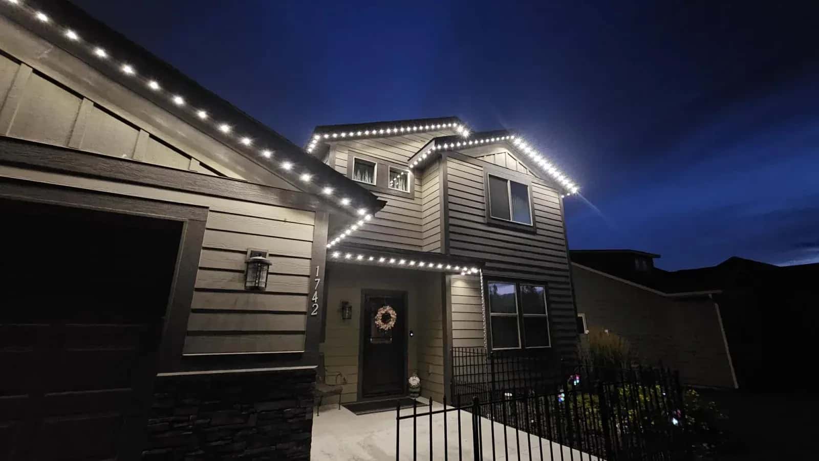 Warm white permanent LED roofline lights outlining a two-storey home at dusk - year-round architectural lighting by Forever Lights