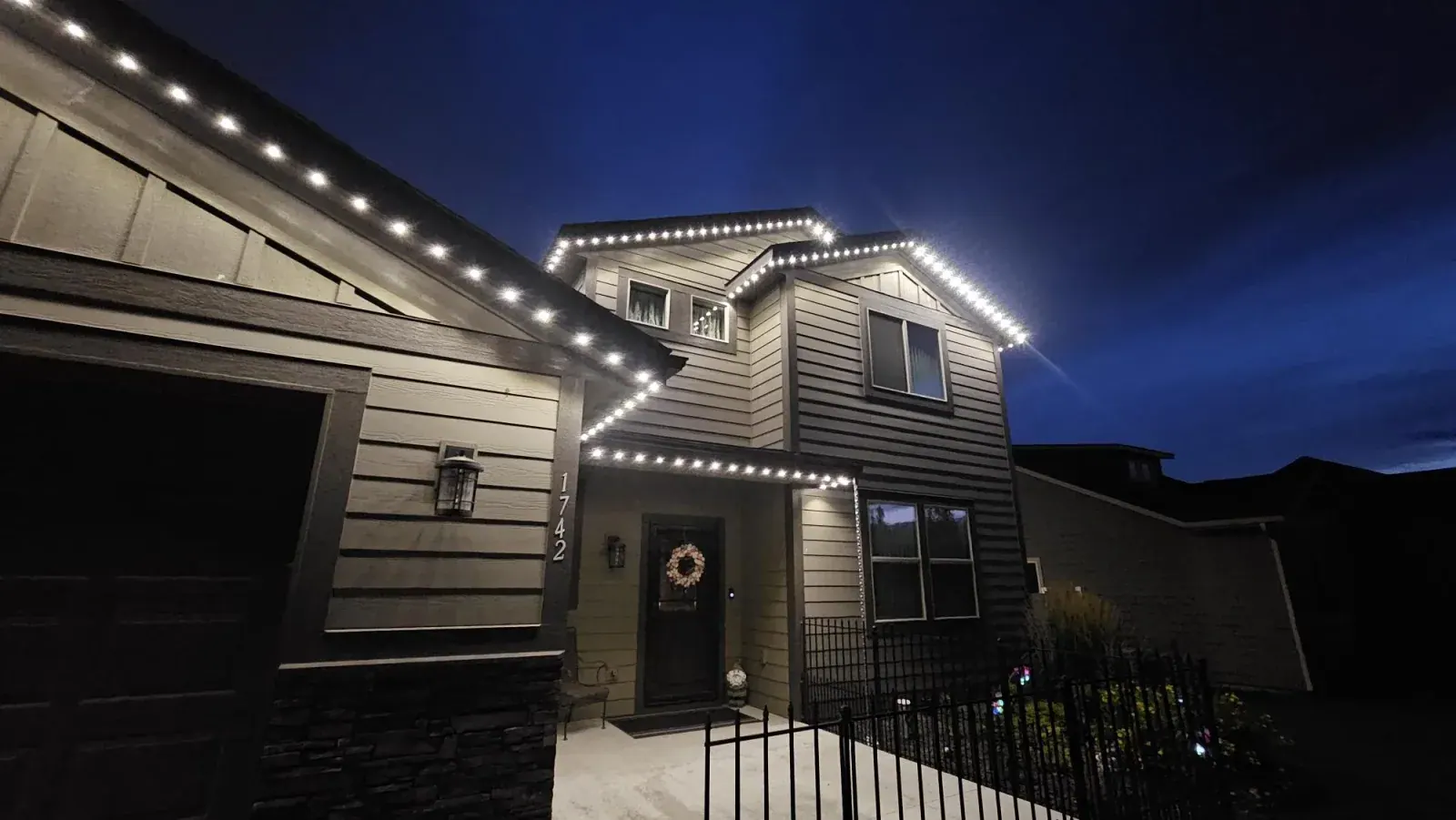 Warm white permanent LED roofline lights outlining a two-storey home at dusk - year-round architectural lighting by Forever Lights