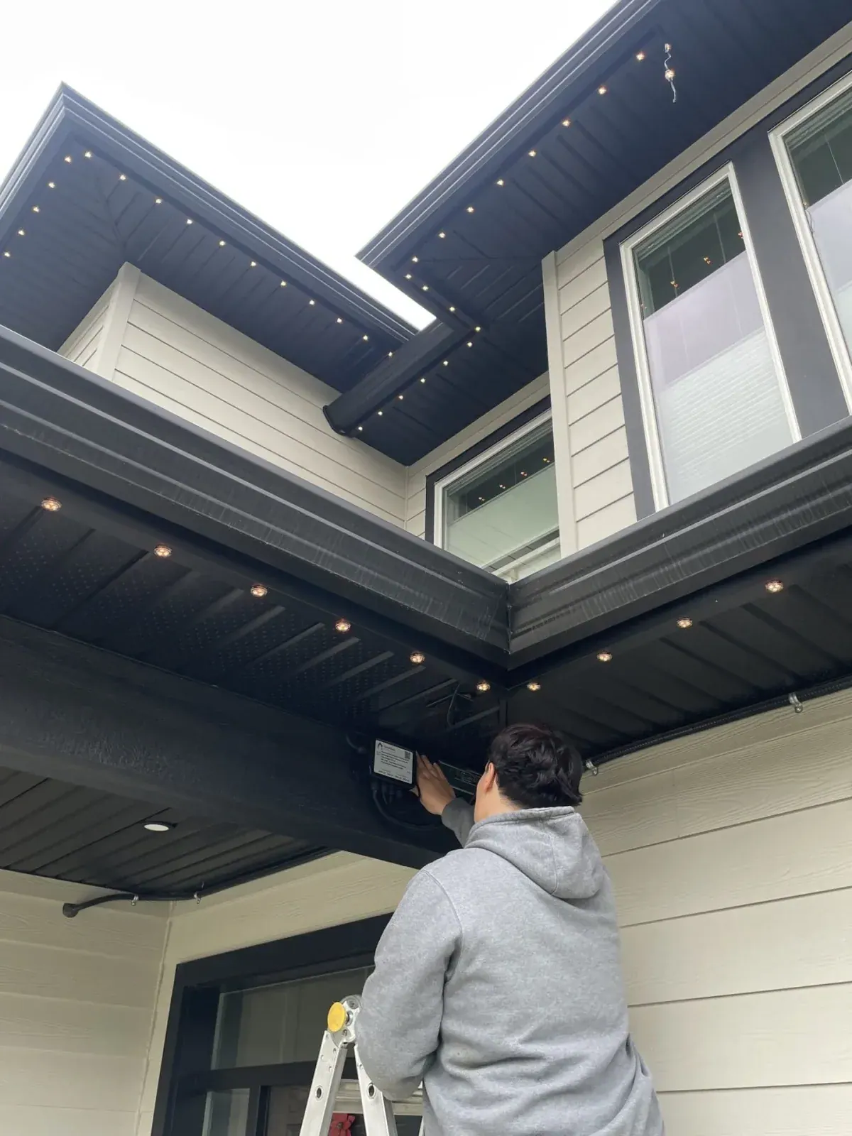 Forever Lights technician installing a permanent LED lighting controller under the soffit of a home